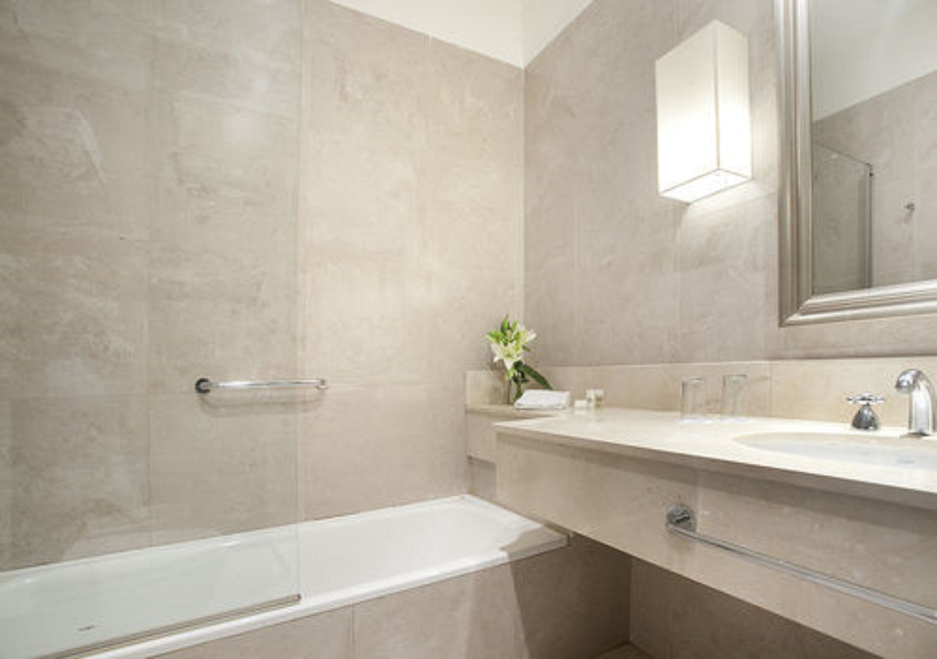 A modern bathroom with a glass-enclosed shower, a white sink, and a mirror above it.