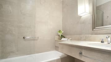 A modern bathroom with a glass-enclosed shower, a white sink, and a mirror above it.