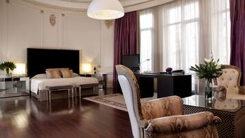 Amplia habitación de hotel con una cama grande, un escritorio, una silla y un televisor.