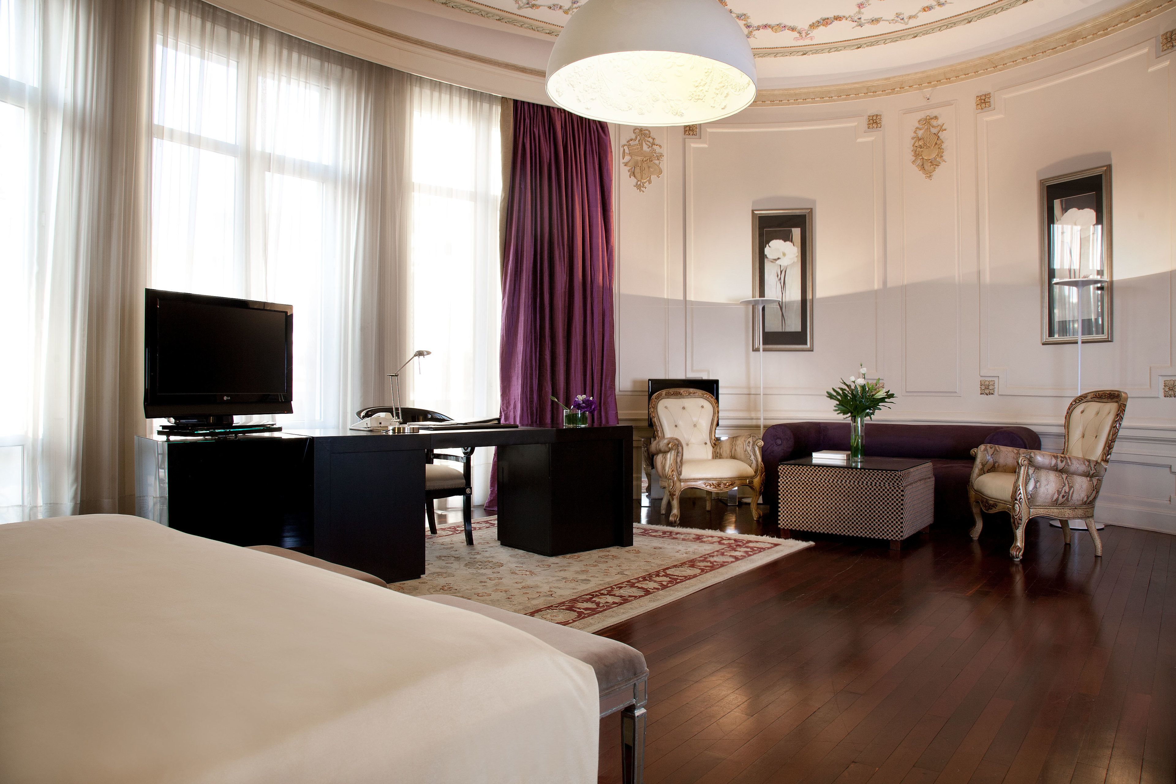 A hotel room with a bed, a desk, a television, a sofa, and a chair.