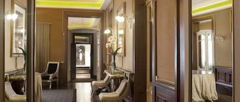 Een hotelgang met vloerbedekking, houten deuren en een spiegel aan de muur.