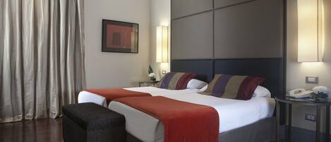 Habitación de hotel con una cama grande, una mesita de noche con lámpara y un teléfono en la pared.