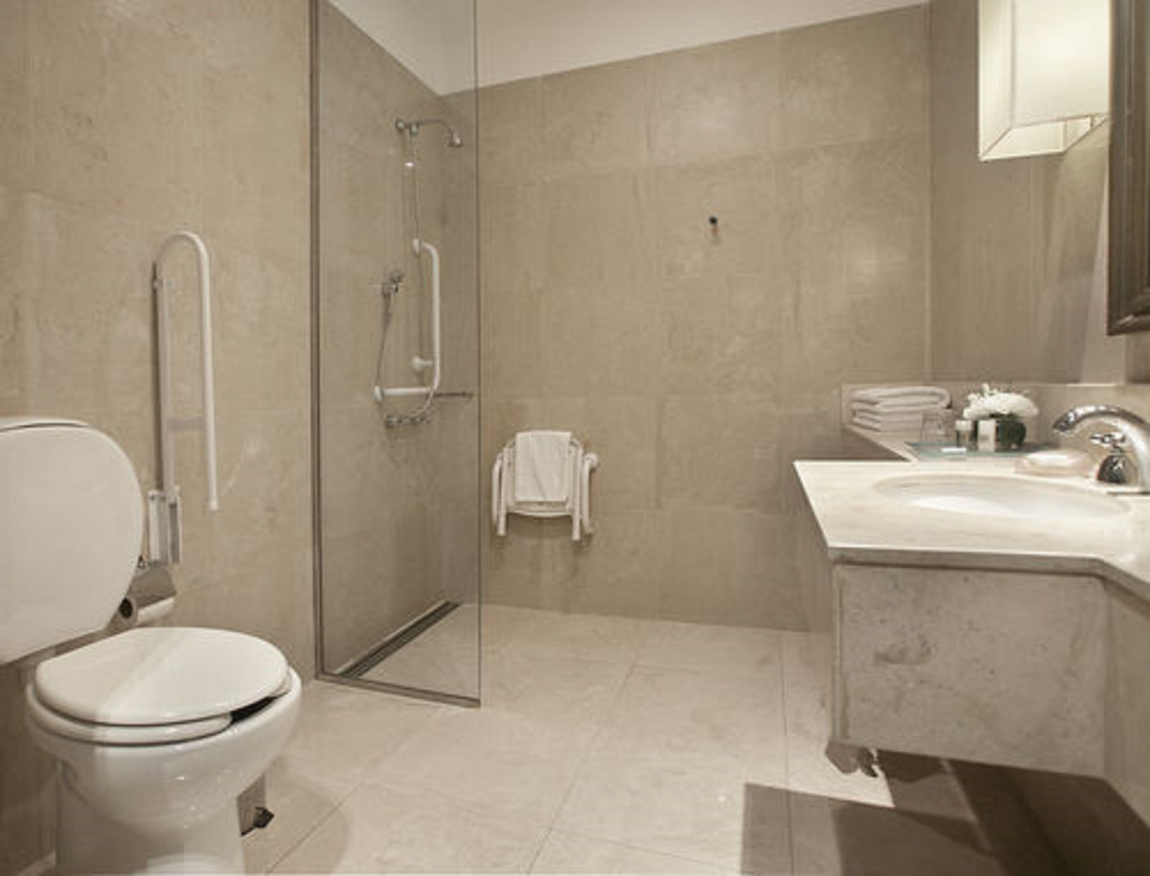 A modern bathroom with a toilet, a glass shower enclosure, and a vanity with a sink and mirror.