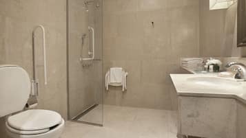 Un baño moderno con inodoro, cabina de ducha de vidrio y tocador con lavabo y espejo.
