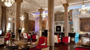 A luxurious hotel lobby with ornate columns, chandeliers, and red and white seating areas. - Savoy Hotel (Buenos Aires)