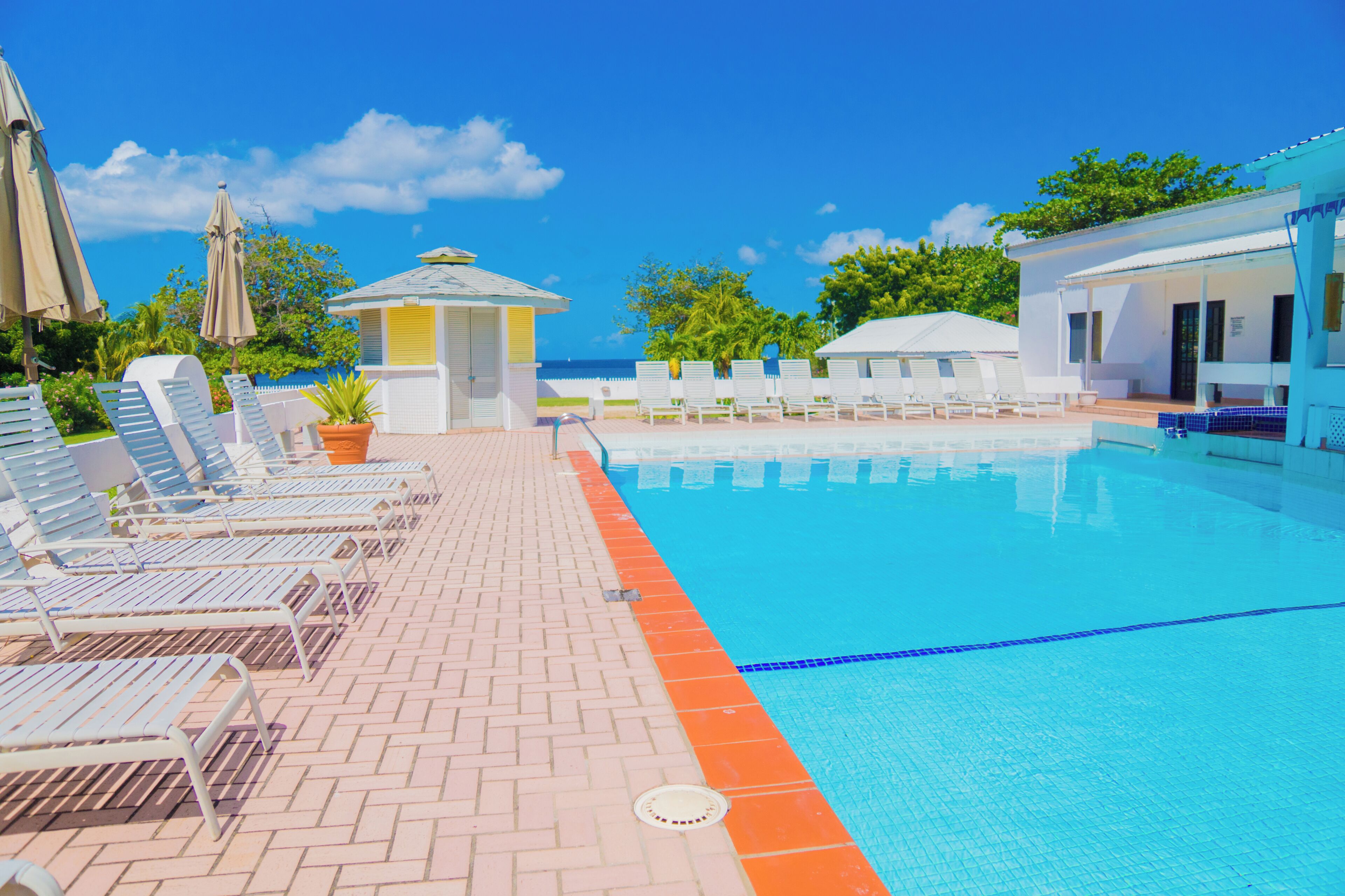 A pool area with lounge chairs, a small gazebo, and a view of the ocean.