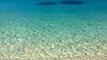 En la playa, arena blanca, sillas reclinables de playa, toallas de playa