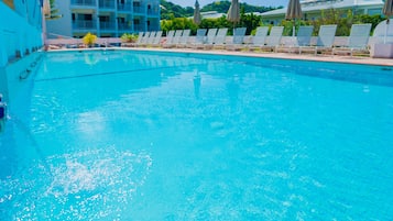 Alberca al aire libre, sombrillas en la alberca y camastros