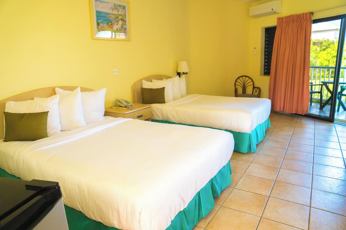 A hotel room with two beds, a desk, a telephone, and a window with a curtain.