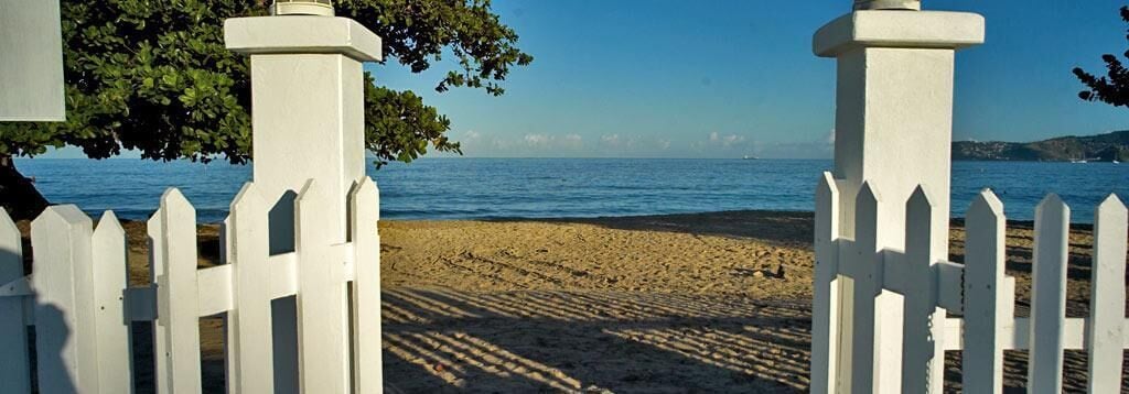 Una playa con cercas blancas y una vista despejada del mar.