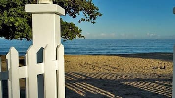A beach with white picket fences and a clear view of the sea.
