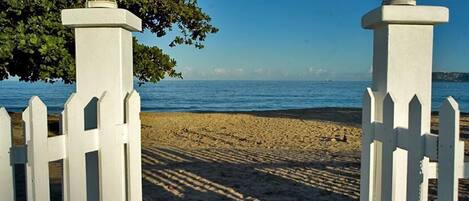 Una playa con cercas blancas y una vista despejada del mar.