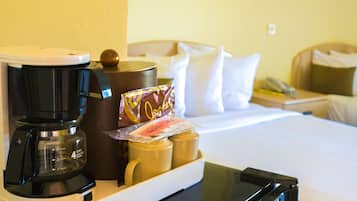 A hotel room with a coffee maker, a bottle of lotion, and a tray with a card on a bedside table.