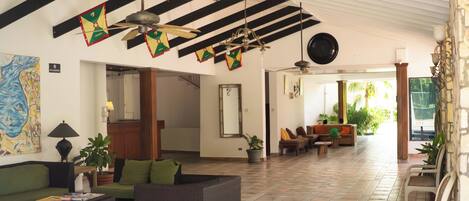 A spacious lobby with a high ceiling, black and white beams, and a mix of seating areas including sofas and chairs.
