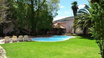 Una piscina al aire libre, sillones reclinables de piscina