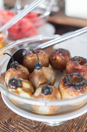 A glass dish containing glazed pears with a caramelized top, placed on a wooden table.