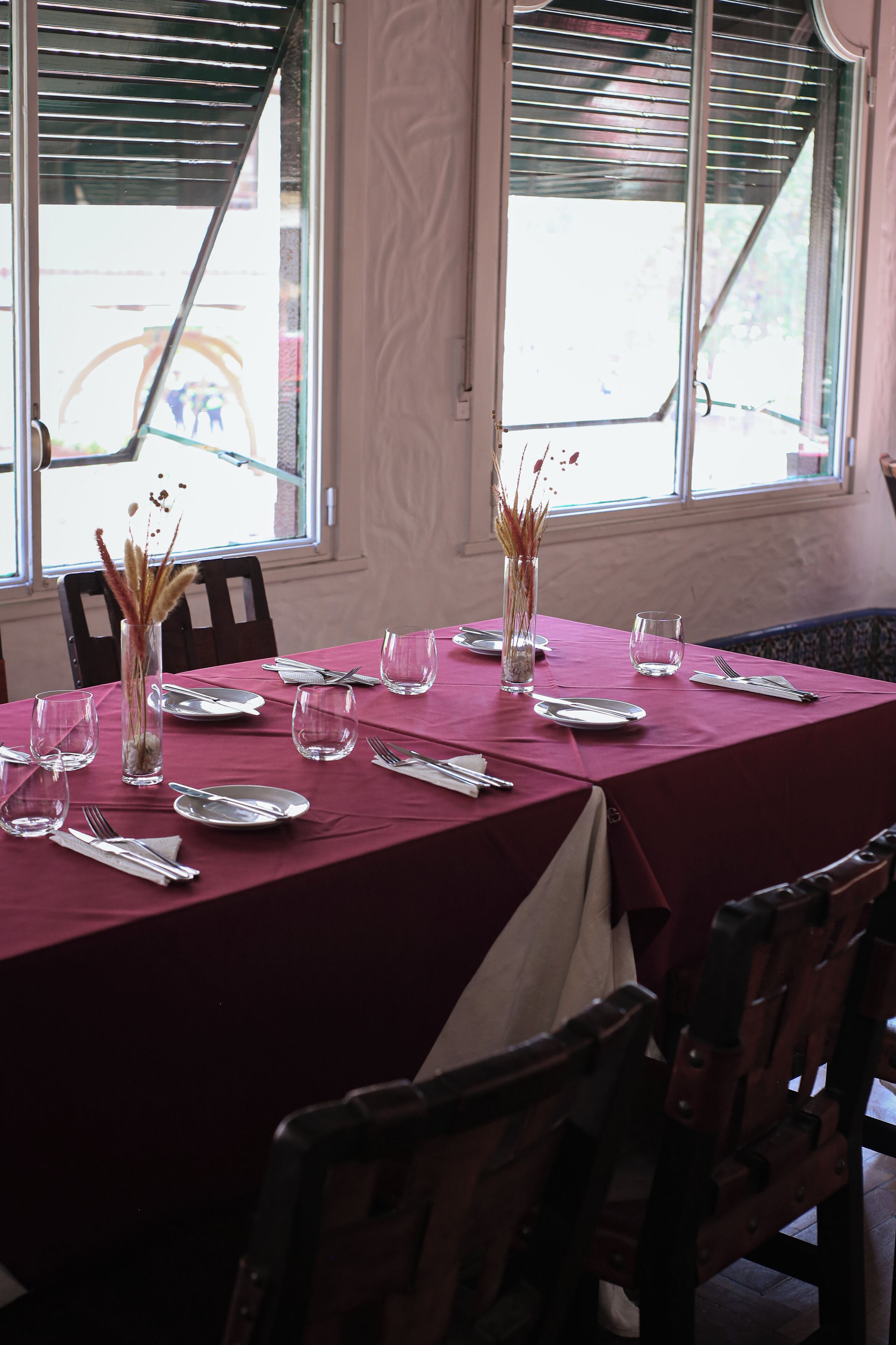 A dining table set with plates, cutlery, and glasses, with chairs around it.