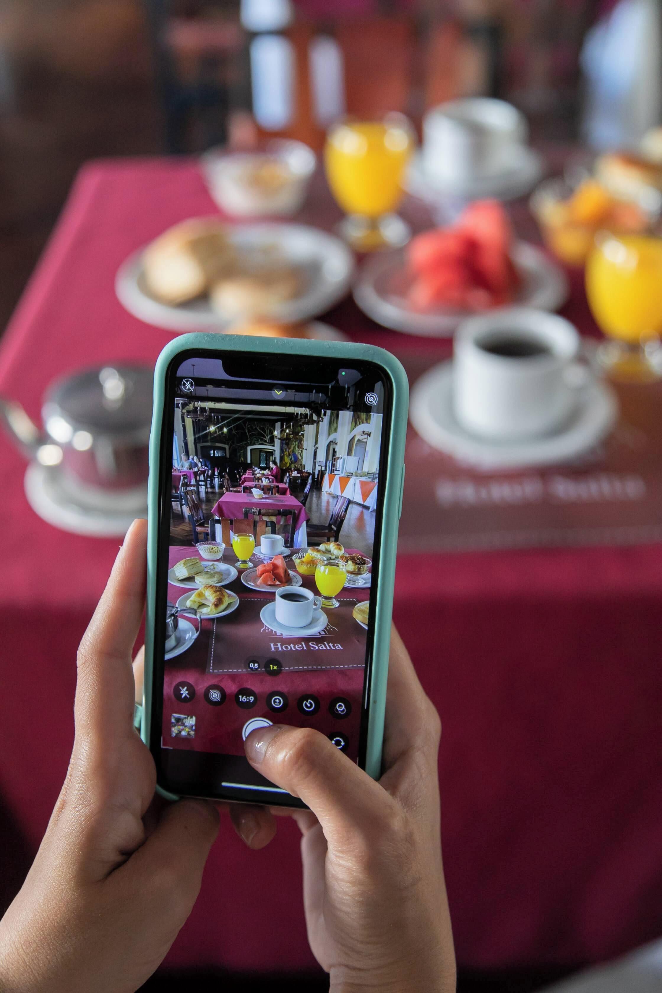 Une personne tenant un téléphone intelligent et photographiant la vue sur le restaurant d’un hôtel.