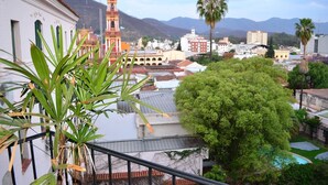 A balcony with a view of a cityscape, including a prominent tower and mountains in the background.