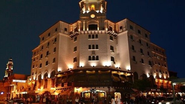 A historic building with a central tower, multiple floors, and a ground-level entrance with a covered area.
