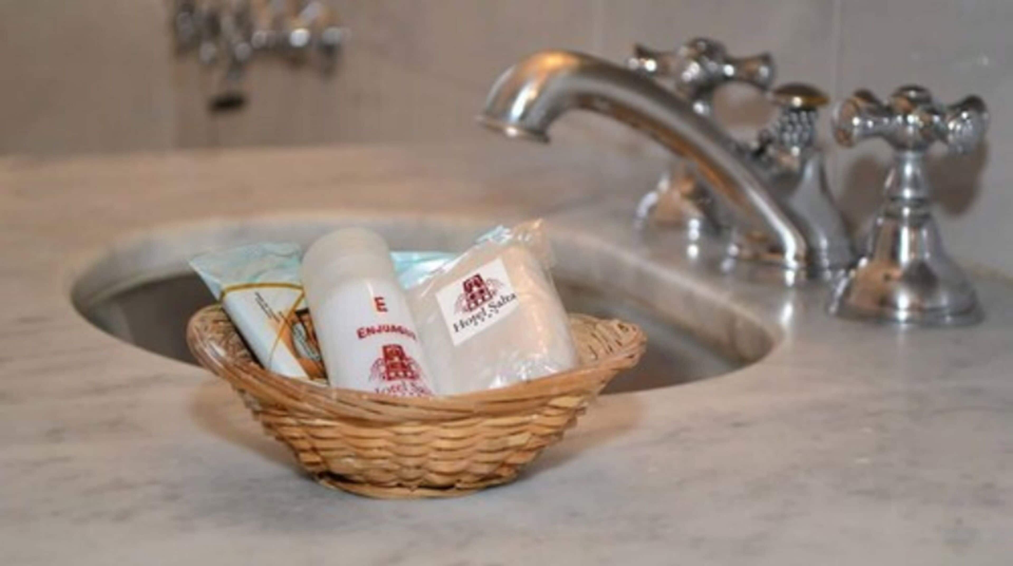 A bathroom sink with a wicker basket containing toiletries.