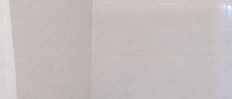 Un baño con bañera, azulejos blancos y un detalle decorativo.