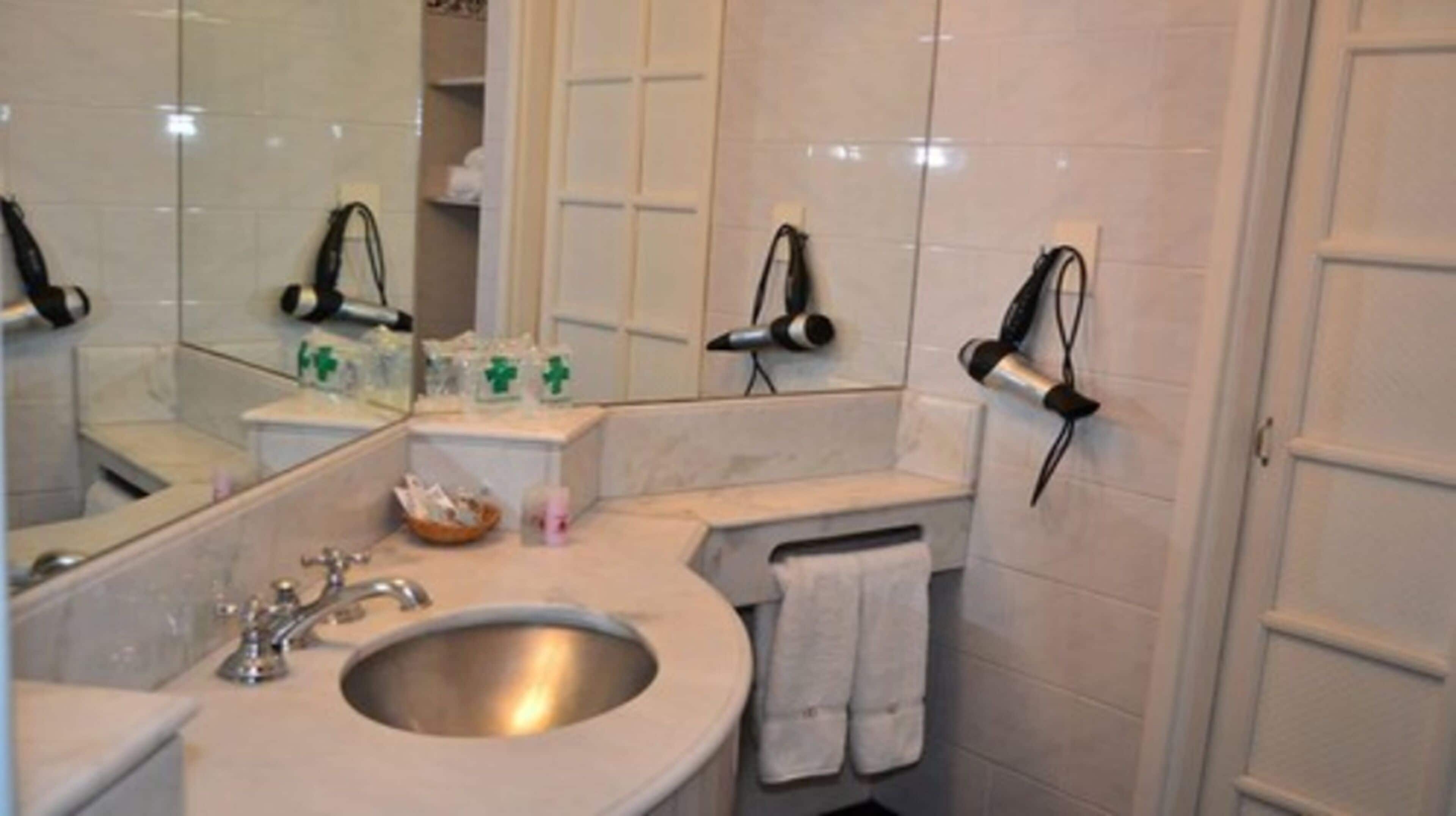 A bathroom with a sink, mirror, towel rack, and toiletries.