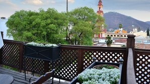 A balcony with a wooden lattice railing, a wooden bench, and potted plants.