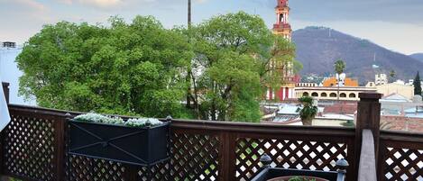 A balcony with a wooden lattice railing, a wooden bench, and potted plants.