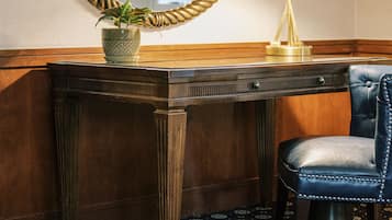 A corner desk with two lamps, a potted plant, and a leather chair.