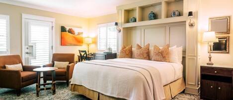 Une chambre d’hôtel avec un grand lit, une chaise, une petite table, un bureau et une lampe.