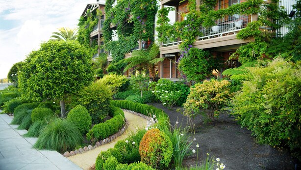 Un hôtel entouré d’une végétation luxuriante, doté d’un chemin sinueux et d’un jardin bien entretenu.