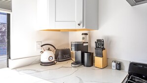 A modern kitchen with a kettle, toaster, coffee maker, salt and pepper shakers, and a knife block. - Hotel Koxie (Los Angeles)