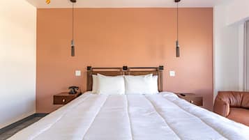 A large bed with a wooden headboard, two bedside tables, and a brown leather chair.