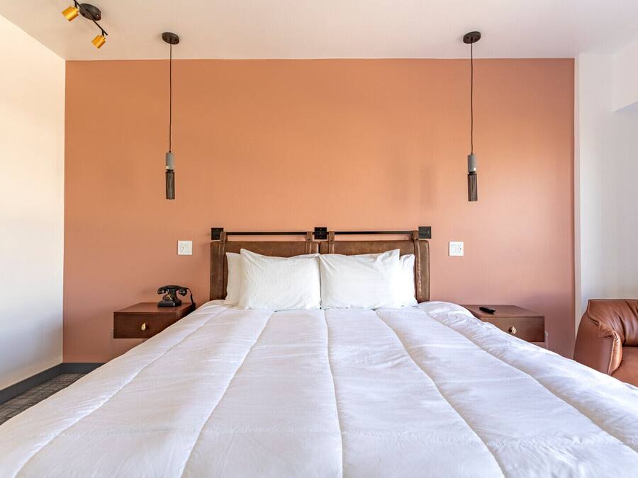 A large bed with a wooden headboard, two bedside tables, and a brown leather chair.