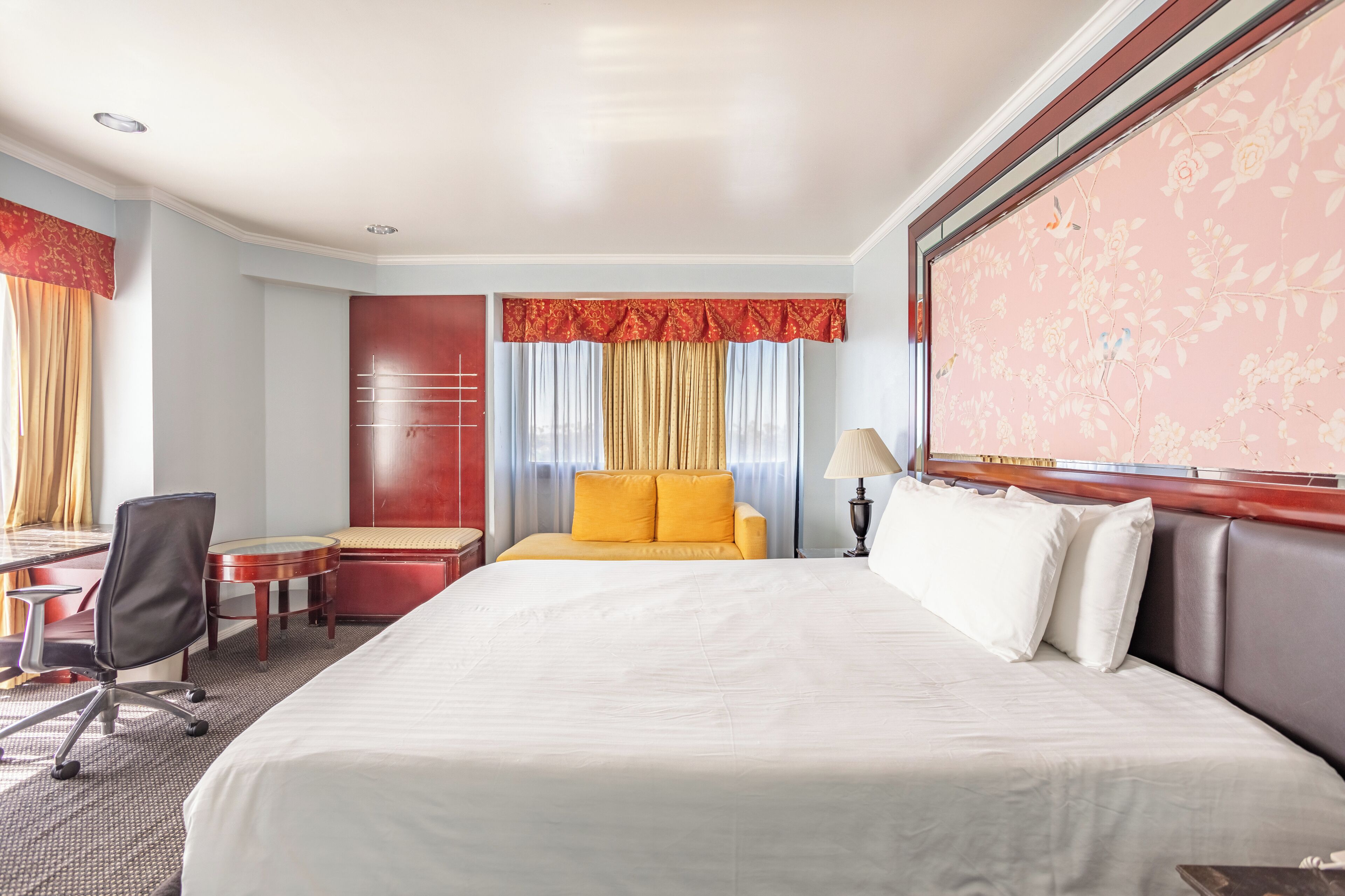 A hotel room with a large bed, a desk, a chair, and a sofa.