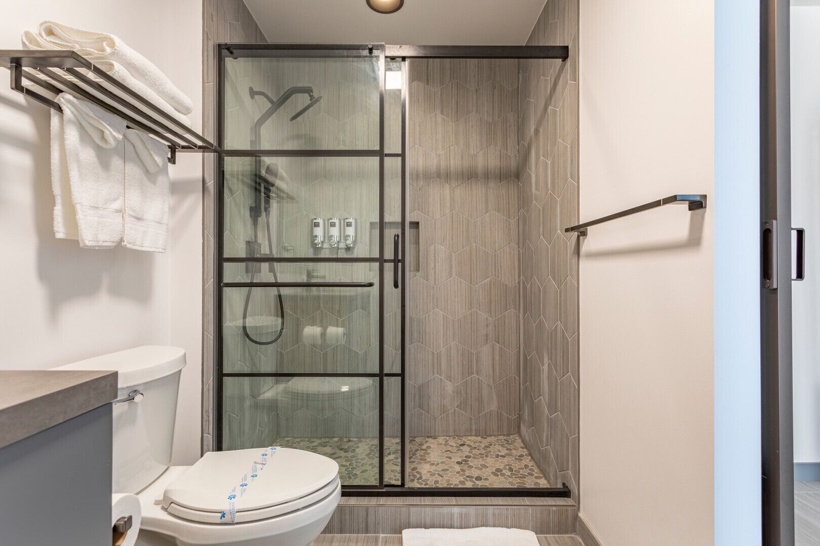 Um banheiro moderno com chuveiro em vidro, vaso sanitário e porta-toalhas.