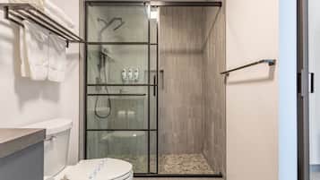 Um banheiro moderno com chuveiro em vidro, vaso sanitário e porta-toalhas.