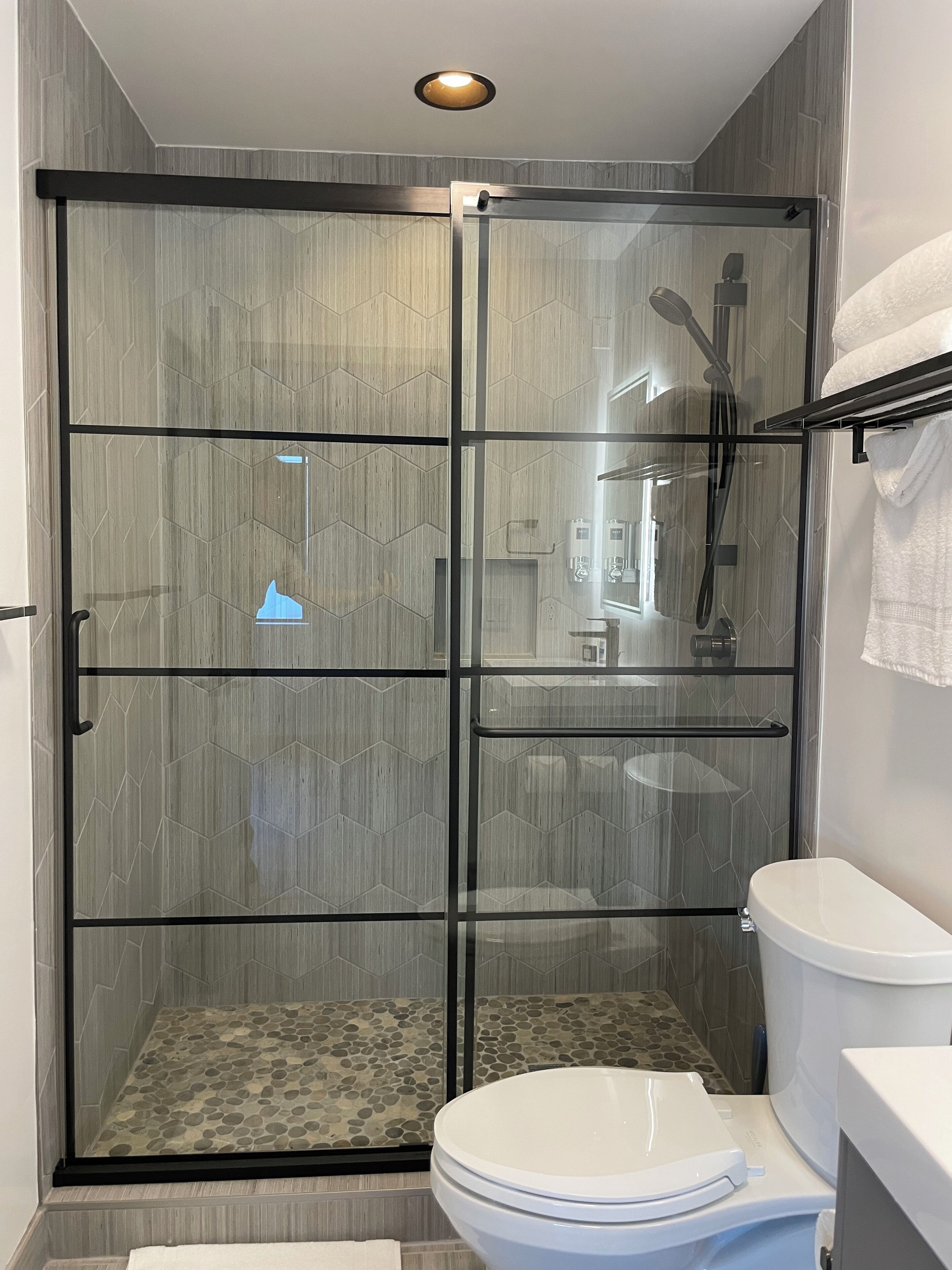 Un baño moderno con ducha de vidrio, inodoro y lavabo.