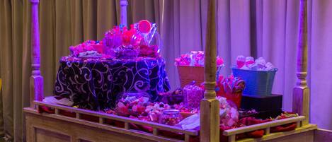 A vintage-style cart with a striped canopy, filled with various items and illuminated by purple lighting.