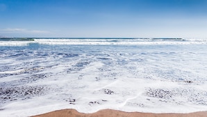 Una playa con olas y cielos despejados.