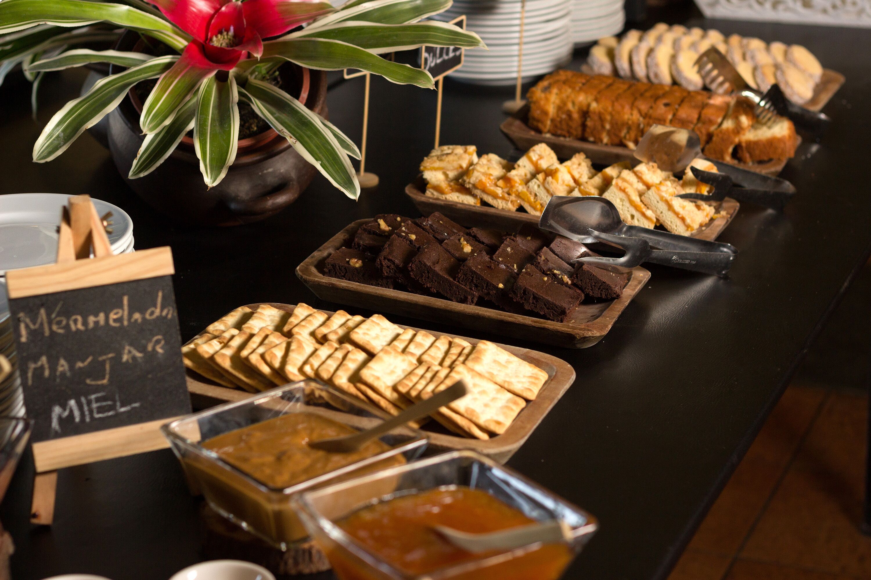 A buffet table with various food items including brownies, pastries, and a sign indicating 'Marmalade, Manjar, Miel'.