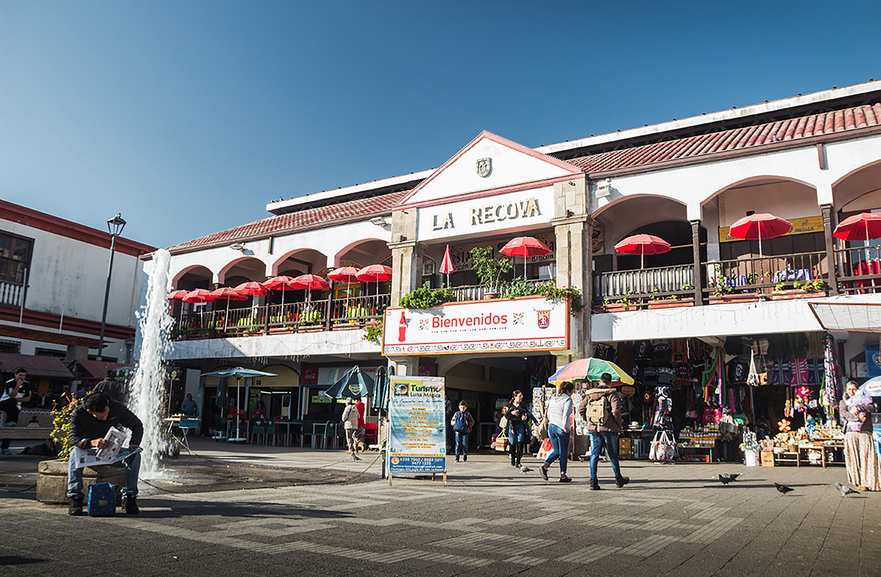 A building with a sign reading "LA RECOVA" and "Bienvenidos" welcoming visitors.