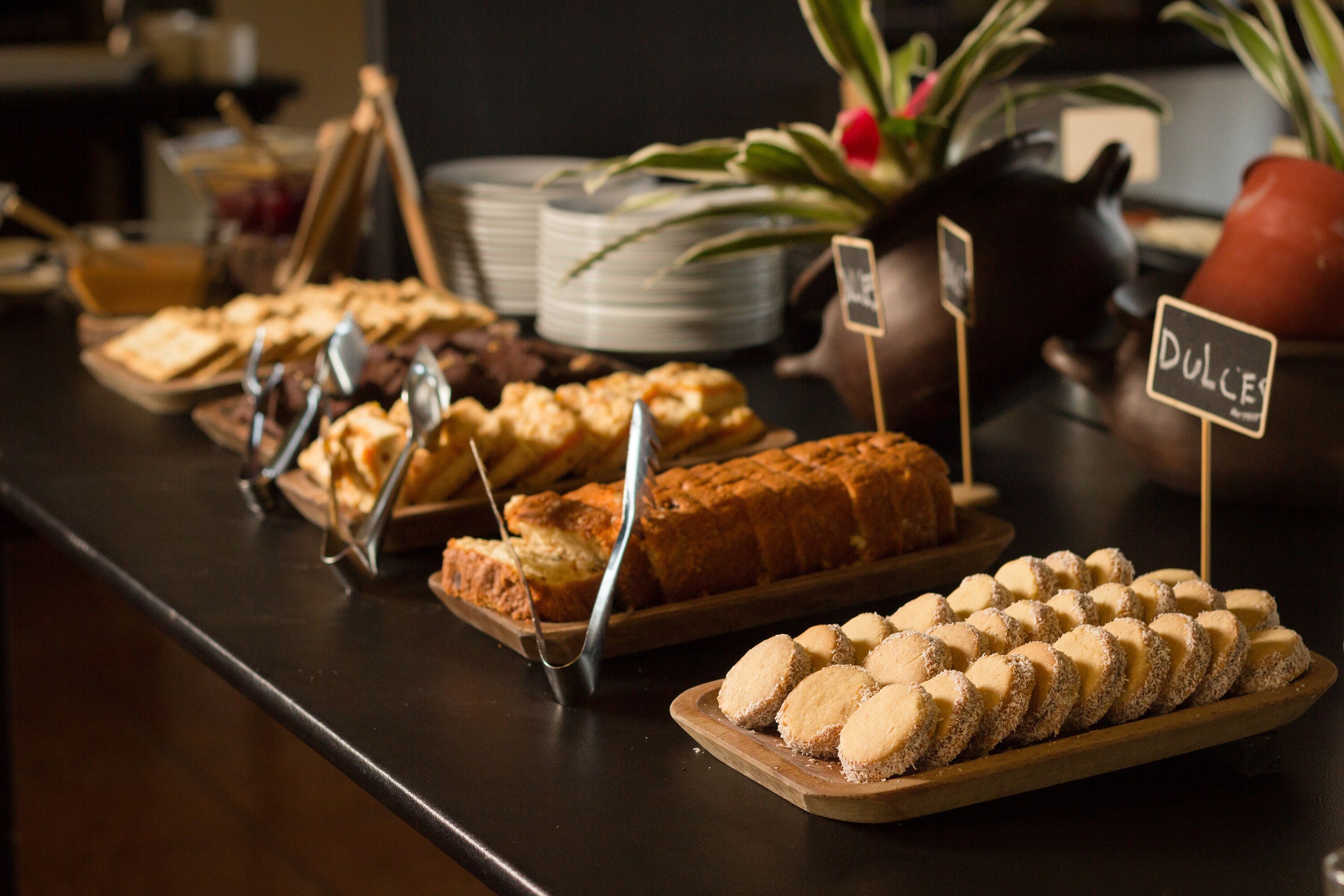 A buffet with various baked goods and desserts, including cakes and cookies, displayed on wooden boards.