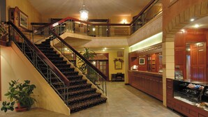 Un vestíbulo amplio con una imponente escalera, una zona de recepción y una exhibición de zapatos.