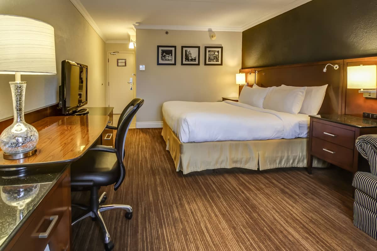 Ett hotellrum med en säng, ett skrivbord, en stol och en tv.