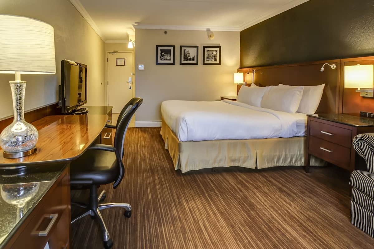 Ett hotellrum med en säng, ett skrivbord, en stol och en tv.