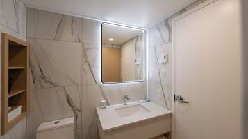 Un baño moderno con pared de mármol, estante de madera, inodoro, lavabo con espejo y perchero.