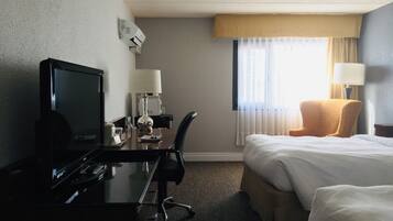 A hotel room with a desk, a bed, a chair, and a television.