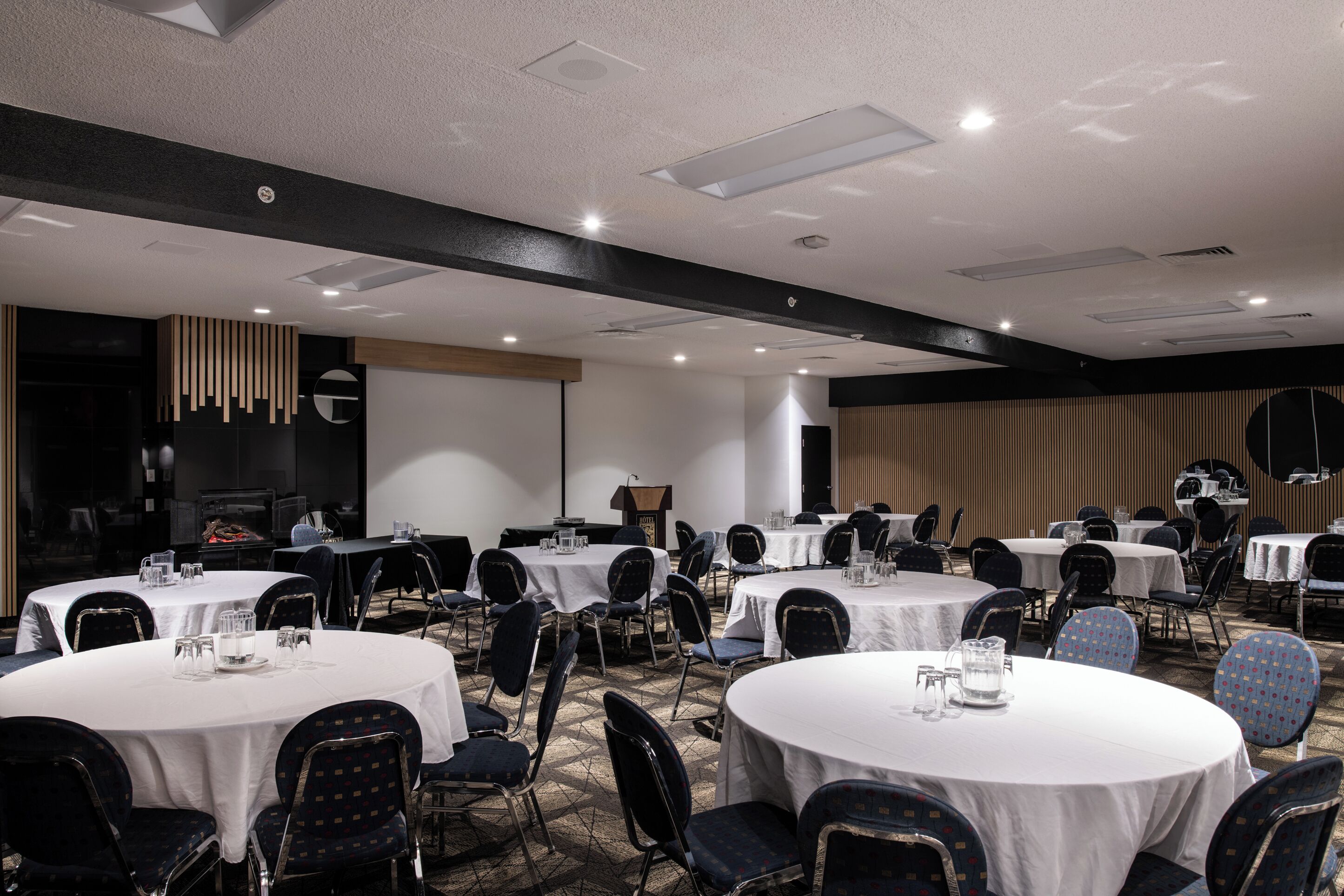 A conference room with multiple round tables, each set with chairs and water glasses.